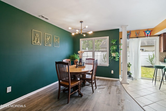 dining room with ornate columns, baseboards, light wood-style flooring, and a chandelier