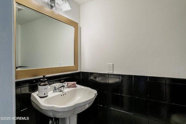 bathroom with a sink, tile walls, and a wainscoted wall