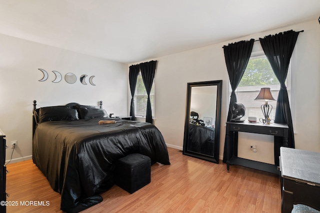 bedroom featuring multiple windows, light wood finished floors, and baseboards