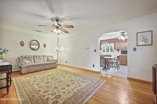 624 Lloyd Rd, Aberdeen, NJ 07747 - living room featuring ceiling fan, arched walkways, light wood finished floors, and a baseboard radiator