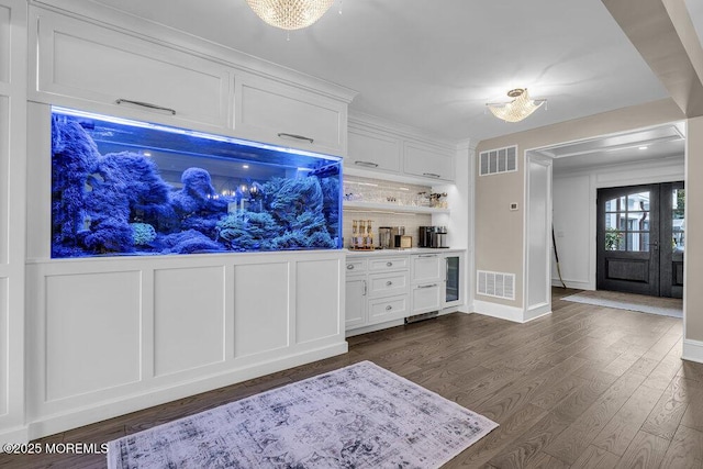 living area with dark wood-style floors, bar with sink, a decorative wall, and beverage cooler