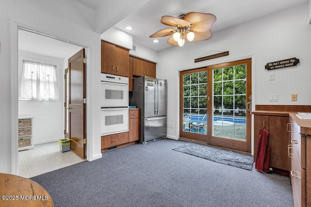 kitchen featuring freestanding refrigerator, double oven, ceiling fan, recessed lighting, and brown cabinets