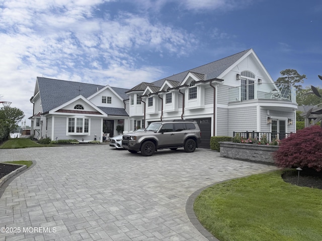 view of front of home with decorative driveway, a garage, and a shingled roof