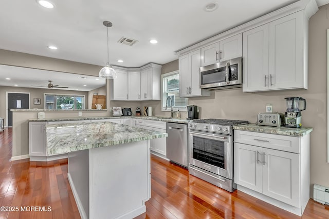 14 Santiago Dr W, Toms River, NJ 08757 - kitchen with stainless steel appliances, a peninsula, a sink, light wood-style flooring, and white cabinetry
