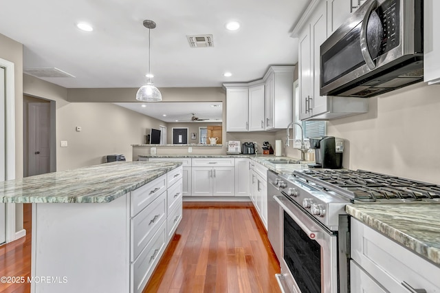 14 Santiago Dr W, Toms River, NJ 08757 - kitchen featuring appliances with stainless steel finishes, a sink, white cabinets, light wood-style flooring, and light stone countertops