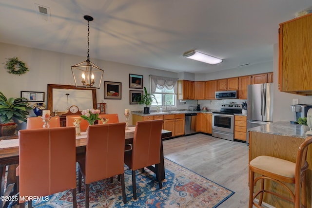 4 Capewoods Rd, North Cape May, NJ 08204 - kitchen featuring stainless steel appliances, a sink, a chandelier, light wood-style flooring, and tasteful backsplash