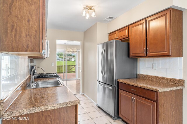 7 Sloop Sq, Freehold, NJ 07728 - kitchen with freestanding refrigerator, a sink, decorative backsplash, light tile patterned floors, and brown cabinetry