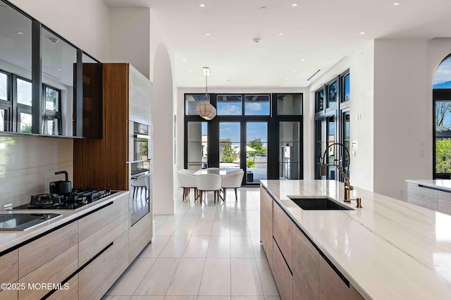 27 N Ward Ave, Rumson, NJ 07760 - kitchen featuring modern cabinets, a sink, arched walkways, light tile patterned floors, and light stone counters