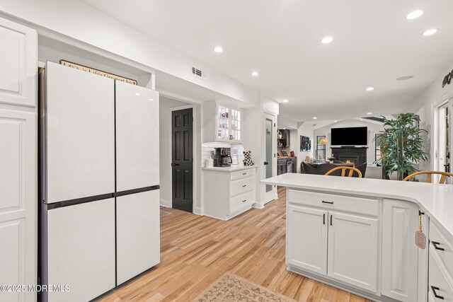 7 Carlisle Ct, Hazlet, NJ 07730 - kitchen with white cabinets, recessed lighting, light wood-type flooring, a warm lit fireplace, and freestanding refrigerator
