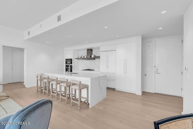 1101 Ocean Ave Unit 1403, Asbury Park, NJ 07712 - kitchen with wall chimney exhaust hood, white cabinets, light wood-type flooring, a sink, and modern cabinets