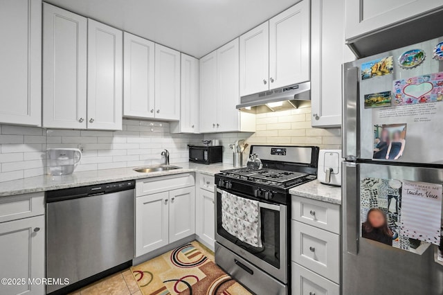 kitchen featuring appliances with stainless steel finishes, under cabinet range hood, a sink, white cabinets, and tasteful backsplash