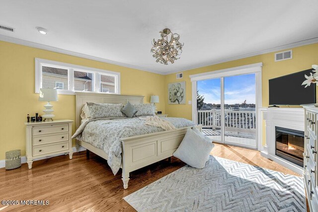 3504 Churchill Dr, Toms River, NJ 08753 - bedroom with access to outside, ornamental molding, a chandelier, a glass covered fireplace, and wood finished floors