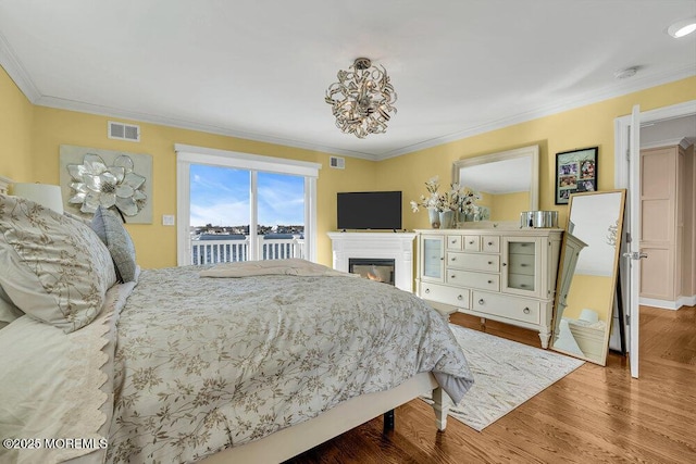 3504 Churchill Dr, Toms River, NJ 08753 - bedroom featuring access to outside, wood finished floors, crown molding, a chandelier, and a glass covered fireplace