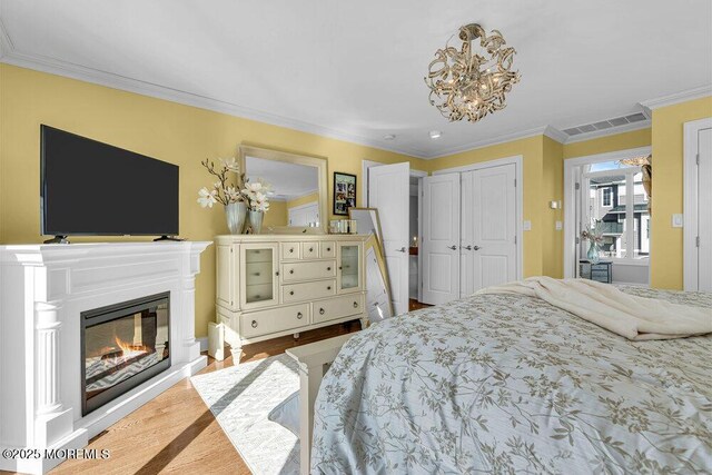 3504 Churchill Dr, Toms River, NJ 08753 - bedroom with ornamental molding, a glass covered fireplace, a chandelier, wood finished floors, and a closet
