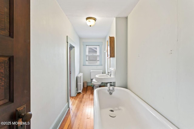 208 4th Ave, Belmar, NJ 07719 - bathroom featuring radiator heating unit, a tub to relax in, hardwood / wood-style floors, baseboards, and toilet