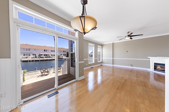 14 Osprey Ln Unit 72, Bayville, NJ 08721 - unfurnished living room with ornamental molding, light wood-style floors, a water view, a ceiling fan, and a glass covered fireplace
