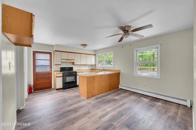 90 Dock Rd, Brick, NJ 08723 - kitchen featuring black gas range, a baseboard heating unit, a peninsula, under cabinet range hood, and light wood-type flooring