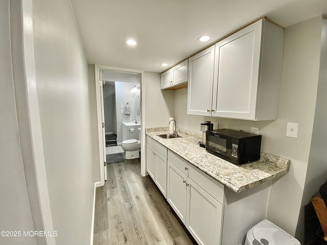 8 Augusta St, Wrightstown, NJ 08562 - kitchen with black microwave, light wood finished floors, a sink, white cabinetry, and light stone counters