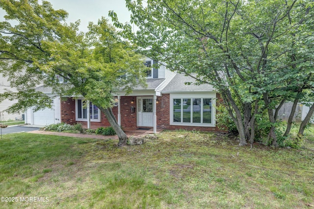 153 12th St, Belford, NJ 07718 - view of property hidden behind natural elements with brick siding, a garage, a front yard, asphalt driveway, and a shingled roof