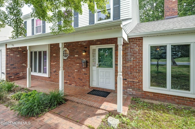 153 12th St, Belford, NJ 07718 - doorway to property featuring brick siding, covered porch, and a chimney