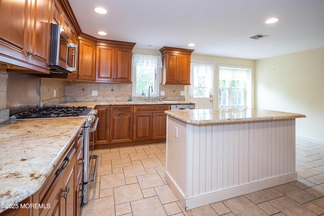 153 12th St, Belford, NJ 07718 - kitchen featuring stainless steel appliances, a sink, a kitchen island, backsplash, and brown cabinets