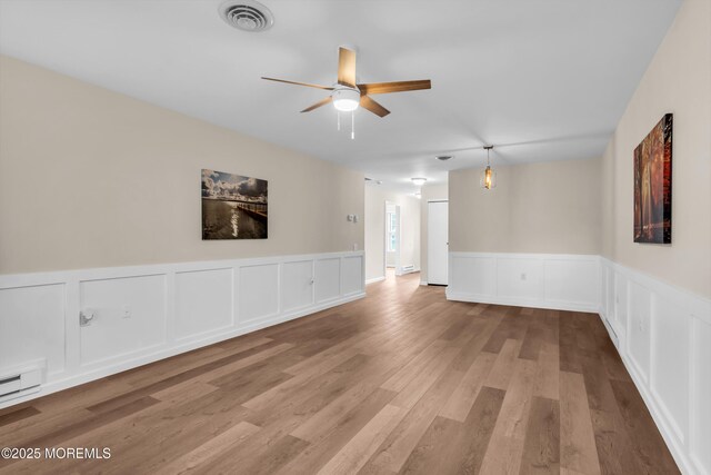28 Mill Rd Unit B, Whiting, NJ 08759 - unfurnished room featuring ceiling fan, a decorative wall, wood finished floors, wainscoting, and a baseboard radiator