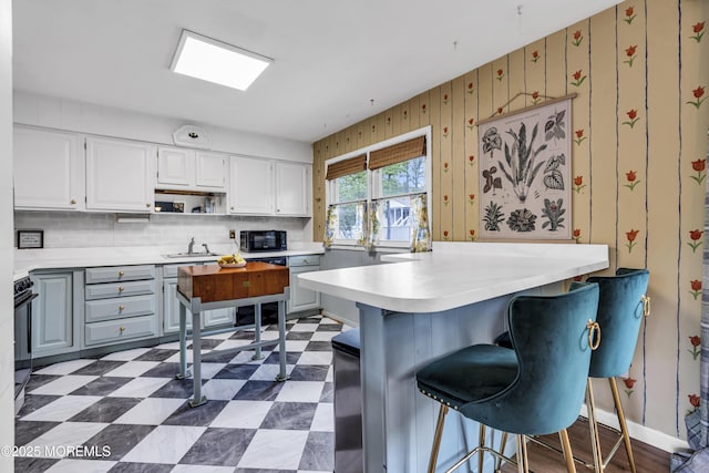 930 Devon St, Forked River, NJ 08731 - kitchen with black microwave, dark flooring, light countertops, a peninsula, and a sink