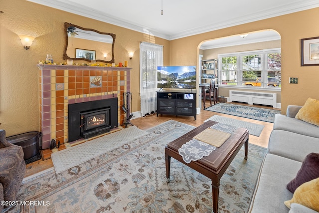 10 Fulton St, Freehold, NJ 07728 - living room featuring radiator heating unit, a textured wall, arched walkways, ornamental molding, and a tiled fireplace
