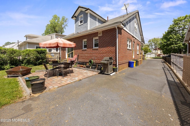 10 Fulton St, Freehold, NJ 07728 - back of property featuring brick siding, a patio, and an outdoor fire pit