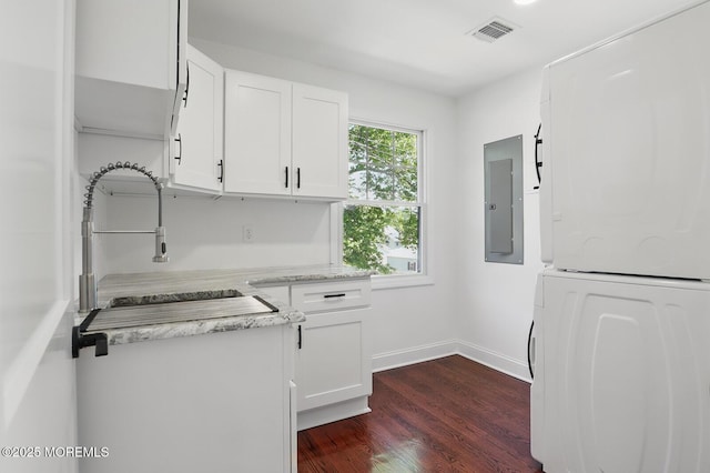 18 Neptune Pl, North Middletown, NJ 07748 - kitchen with stacked washer / drying machine, dark wood-style flooring, white cabinets, electric panel, and baseboards