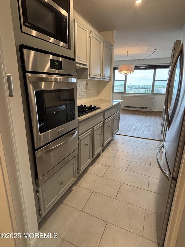 28 Riverside Ave Unit 9G, Red Bank, NJ 07701 - kitchen with stainless steel appliances, a warming drawer, a chandelier, backsplash, and light tile patterned flooring