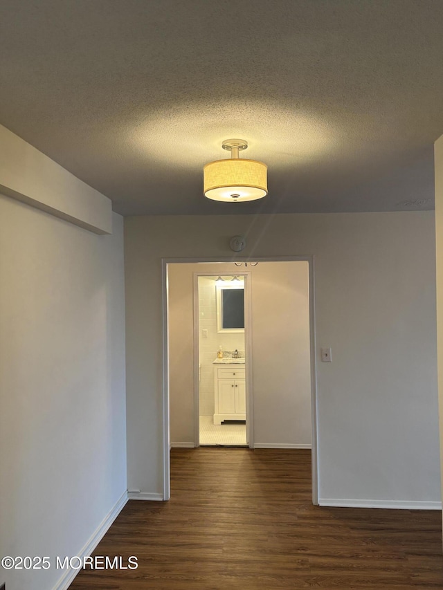 28 Riverside Ave Unit 9G, Red Bank, NJ 07701 - empty room featuring dark wood-style flooring, baseboards, a textured ceiling, and a smoke detector