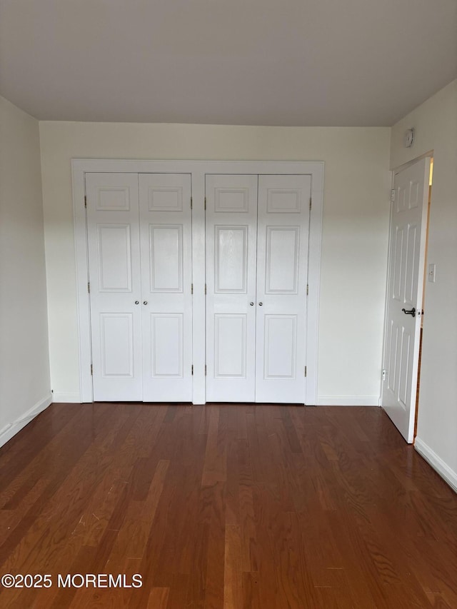 28 Riverside Ave Unit 9G, Red Bank, NJ 07701 - unfurnished bedroom with dark wood-type flooring, baseboards, and multiple closets