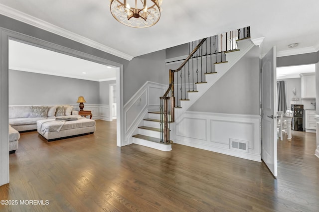 25 Briar Hill Dr, Manalapan, NJ 07726 - staircase with a wainscoted wall, crown molding, a chandelier, a decorative wall, and wood finished floors