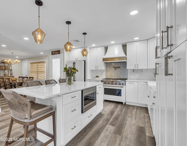 25 Glenview Rd, North Caldwell, NJ 07006 - kitchen featuring range with gas cooktop, custom exhaust hood, freestanding refrigerator, stainless steel microwave, and a breakfast bar area