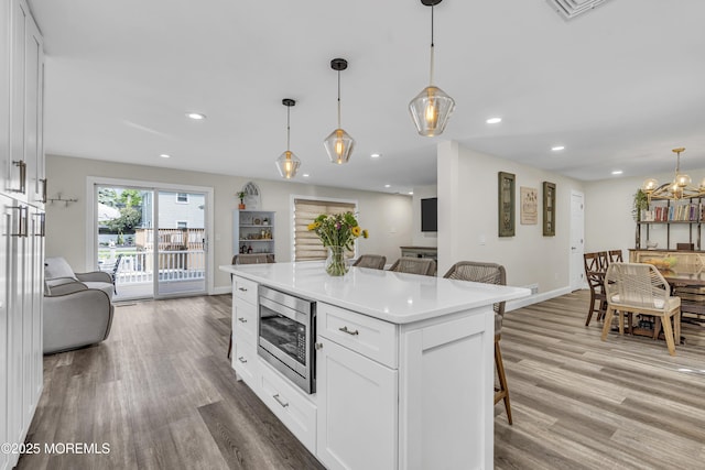 25 Glenview Rd, North Caldwell, NJ 07006 - kitchen featuring stainless steel microwave, a kitchen breakfast bar, white cabinetry, light wood-style flooring, and light countertops