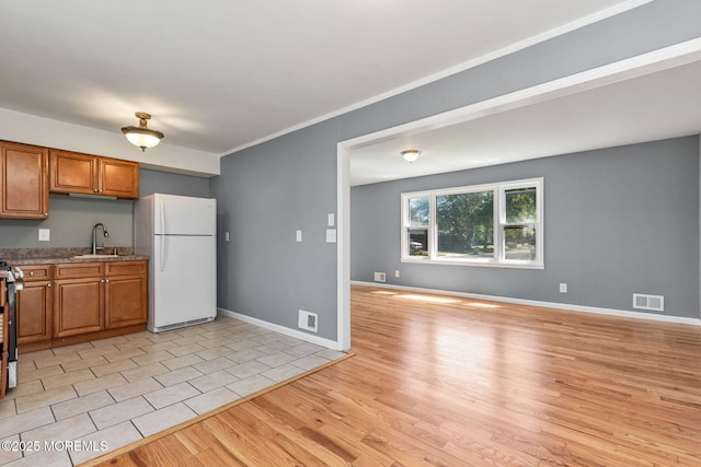 7 Beechwood Ave, Keansburg, NJ 07734 - kitchen featuring freestanding refrigerator, a sink, brown cabinetry, light wood-style flooring, and stainless steel gas stove