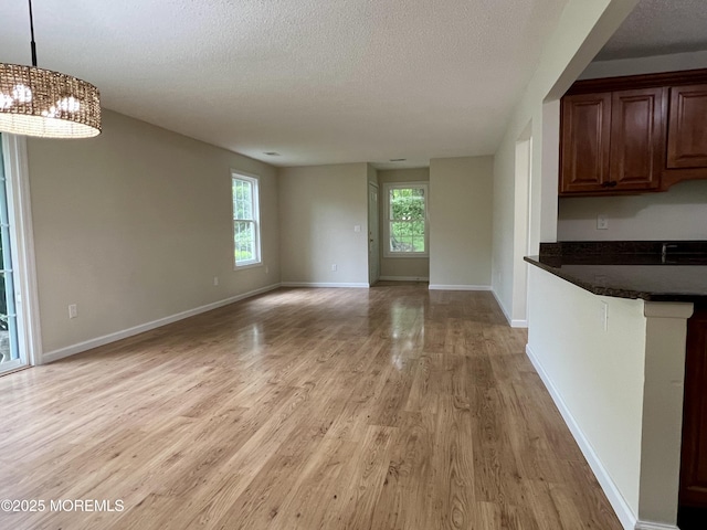5 Lincoln Ct, Tinton Falls, NJ 07712 - unfurnished living room with light wood-type flooring, a textured ceiling, a chandelier, and baseboards