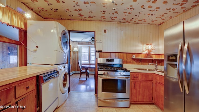 116 Hudson Ave, Hazlet, NJ 07734 - kitchen featuring appliances with stainless steel finishes, stacked washer and clothes dryer, a sink, brown cabinetry, and ceiling fan