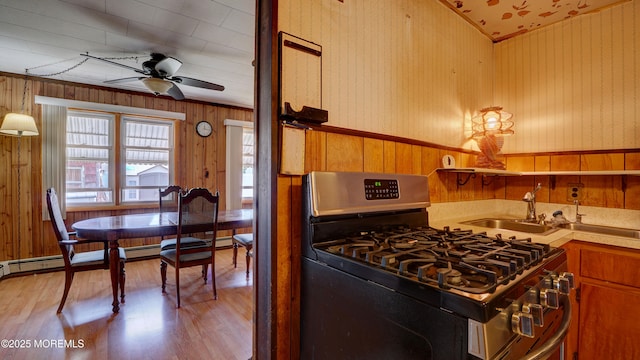 116 Hudson Ave, Hazlet, NJ 07734 - kitchen with stainless steel gas range, a ceiling fan, light wood-type flooring, wooden walls, and a sink