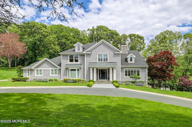 12 Wagon Way, Holmdel, NJ 07733 - view of front of property with a front lawn, a chimney, view of scattered trees, and a standing seam roof