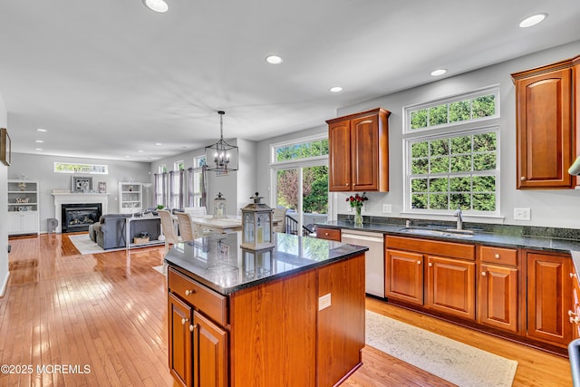 707 Cedar Point Ct, Toms River, NJ 08753 - kitchen with dishwashing machine, a sink, light wood-style floors, a kitchen island, and a glass covered fireplace