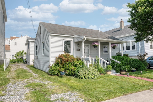 1707-1705 N Bayview Ave, Seaside Park, NJ 08752 - view of front of house with a front lawn, a shingled roof, and a chimney