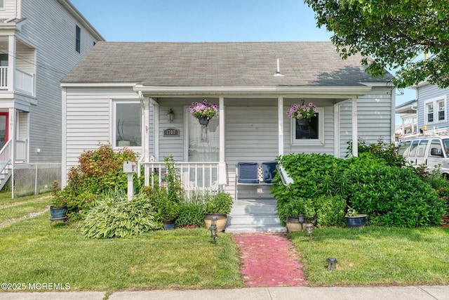 1707-1705 N Bayview Ave, Seaside Park, NJ 08752 - view of front of house featuring covered porch, a front lawn, and roof with shingles