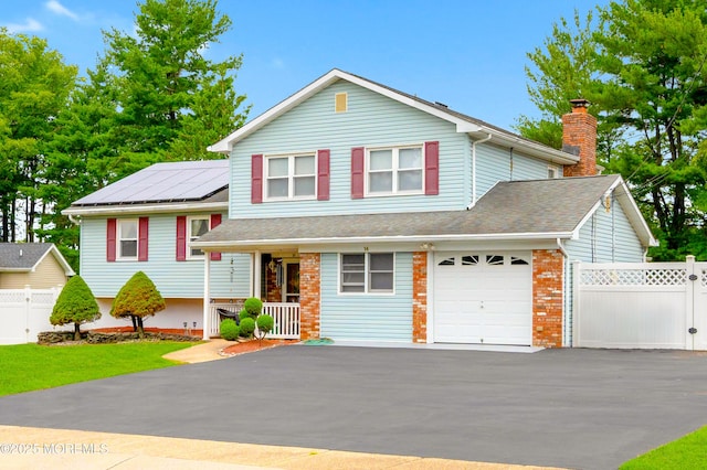 14 N Longview Rd, Howell, NJ 07731 - split level home featuring asphalt driveway, an attached garage, a chimney, and roof mounted solar panels