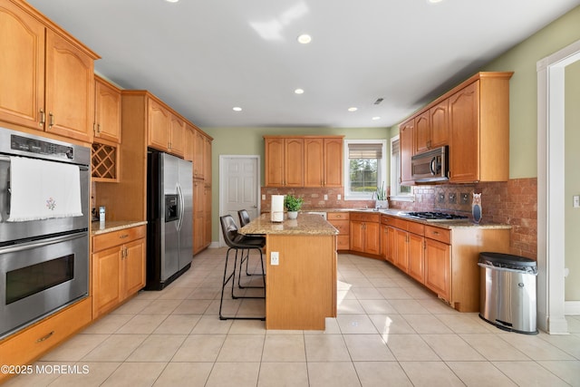 10 Emma Ln, Jackson, NJ 08527 - kitchen featuring appliances with stainless steel finishes, a breakfast bar, a center island, light stone countertops, and decorative backsplash