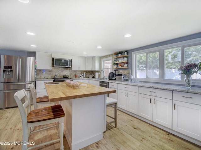 30 Mountain Ave, Hazlet, NJ 07730 - kitchen featuring appliances with stainless steel finishes, butcher block countertops, a breakfast bar area, decorative backsplash, and light wood-style floors