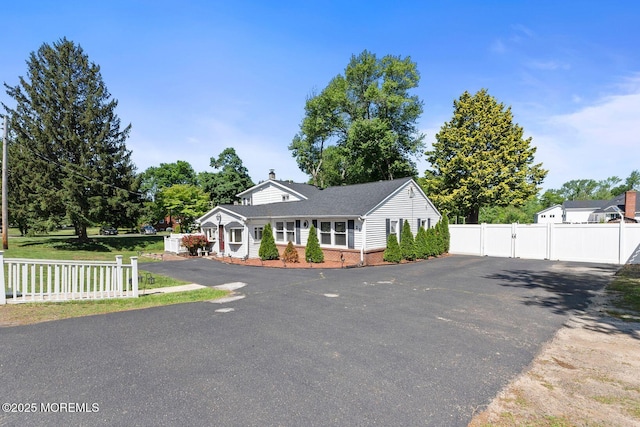 21 Wickatunk Rd, Manalapan, NJ 07726 - view of front facade with brick siding, a gate, driveway, and a chimney