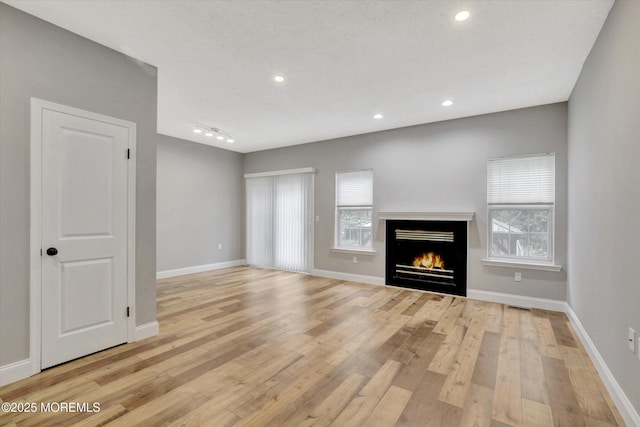 1103 Creamery Ct, Freehold, NJ 07728 - unfurnished living room with plenty of natural light, light wood-type flooring, a lit fireplace, and recessed lighting