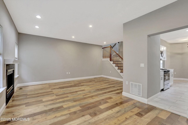 1103 Creamery Ct, Freehold, NJ 07728 - unfurnished living room featuring stairway, light wood-style floors, plenty of natural light, a fireplace, and recessed lighting